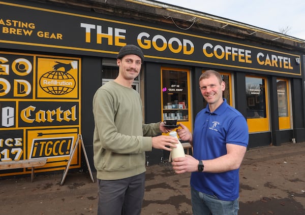 This undated handout photo shows farmer and owner of Mossgiel Organic Farm Bryce Cunningham, right, giving a bottle of milk to barista Jacob Smith, outside The Good Coffee Cartel in Glasgow, Scotland. (Mossgiel Organic Dairy via AP)