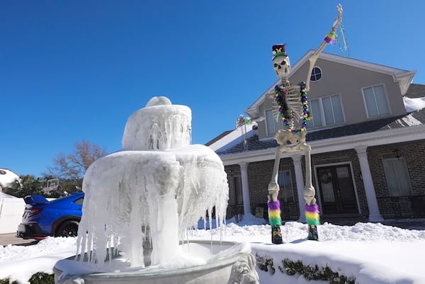 An ice covered fountain sits in front of a Mardi Gras festooned skeleton the day after a rare and record setting snowstorm in River Ridge, La., a suburb of New Orleans, Wednesday, Jan. 22, 2025. (AP Photo/Gerald Herbert)