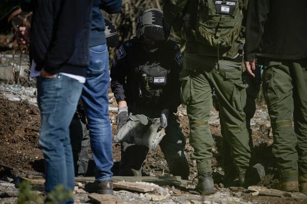 Police bomb squad officers collect the pieces of a rocket fired from Lebanon that landed in a backyard in Kiryat Shmona, northern Israel, Tuesday Nov. 26, 2024. (AP Photo/Leo Correa)