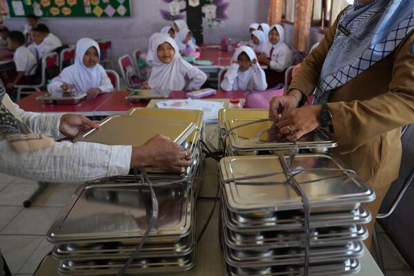 Teachers prepare meals for students during the kick off of President Prabowo Subianto's ambitious free meal program to feed children and pregnant women nationwide despite critics saying that its required logistics could hurt Indonesia's state finances and economy, at an elementary school in Depok, West Java, Indonesia, Monday, Jan. 6, 2025. (AP Photo/Dita Alangkara)