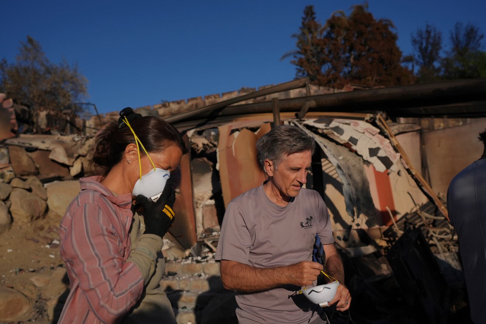 Heidi Nardoni, left, and Peter Banks adjust masks as they search her home destroyed by the Mountain Fire in Camarillo, Calif., Friday, Nov. 8, 2024. (AP Photo/Jae C. Hong)