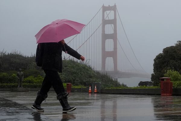 A pedestrian carrying an umbrella walks in front of the Golden Gate Bridge in San Francisco, Wednesday, Nov. 20, 2024. (AP Photo/Jeff Chiu)