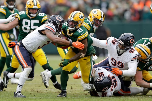 Green Bay Packers running back Josh Jacobs (8) runs against Chicago Bears safety Kevin Byard III, left, defensive tackle Chris Williams (91) and defensive tackle Gervon Dexter Sr. (99) during the first half of an NFL football game, Sunday, Jan. 5, 2025, in Green Bay, Wis. (AP Photo/Matt Ludtke)