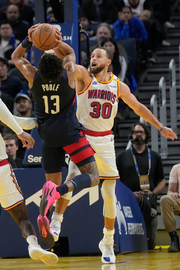 Golden State Warriors guard Stephen Curry (30) blocks a shot by Washington Wizards guard Jordan Poole (13) during the second half of an NBA basketball game in San Francisco, Saturday, Jan. 18, 2025. (AP Photo/Jeff Chiu)