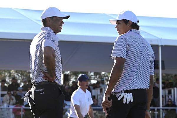 Tiger Woods, left, talks with his son Charlie Woods, right, after finishing on the 18th green during the first round of the PNC Championship golf tournament, Saturday, Dec. 21, 2024, in Orlando. (AP Photo/Phelan M. Ebenhack)