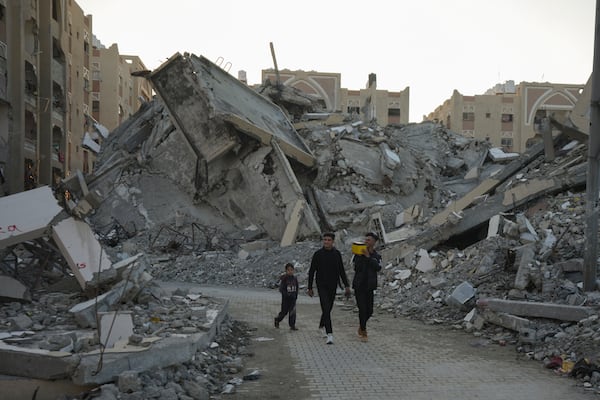 Young Palestinians walk amongst rubble of destroyed buildings at a neighbourhood in Khan Younis, Gaza Strip, Sunday, Dec. 1, 2024. (AP Photo/Abdel Kareem Hana)