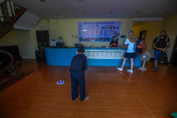 A woman swipes the floor as foreign tourists check out of Nana Backpack hostel in Vang Vieng, Laos, Tuesday, Nov. 19, 2024. (AP Photo/Anupam Nath)