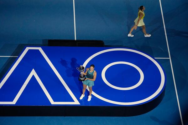 Madison Keys of the U.S. holds the Daphne Akhurst Memorial Cup aloft after defeating Aryna Sabalenka of Belarus, right, in the women's singles final at the Australian Open tennis championship in Melbourne, Australia, Saturday, Jan. 25, 2025. (AP Photo/Manish Swarup)