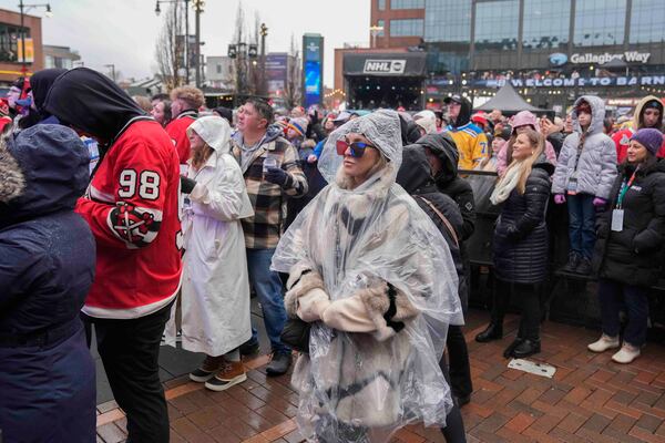 Fans watch pregame entertainment in the rain before the NHL Winter Classic outdoor hockey game between the Chicago Blackhawks and St. Louis Blues at Wrigley Field, Tuesday, Dec. 31, 2024, in Chicago. (AP Photo/Erin Hooley)