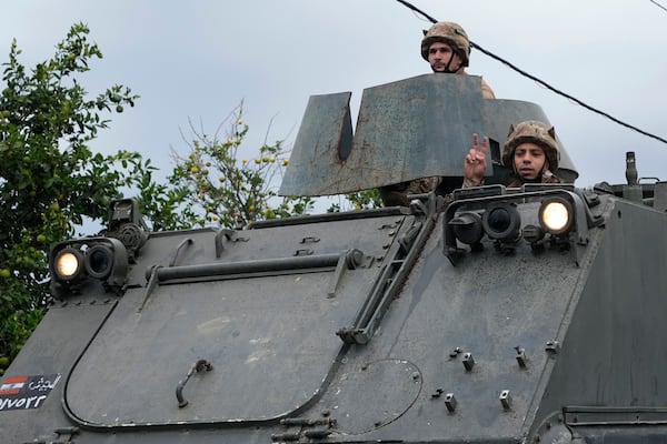 A Lebanese army soldier on an APC (Armored Personnel Carrier) flashes victory sign, as a convoy enters in Mansouri village on its way to being deployed in southern Lebanon, following a ceasefire between Israel and Hezbollah that went into effect on Wednesday, Nov. 27, 2024.(AP Photo/Hussein Malla)