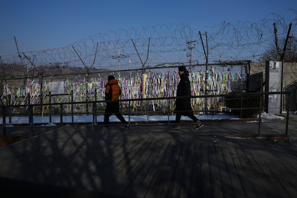 Visitors walk near a wire fence decorated with ribbons written with messages wishing for the reunification of the two Koreas at the Imjingak Pavilion in Paju, South Korea, Wednesday, Jan. 29, 2025. (AP Photo/Lee Jin-man)