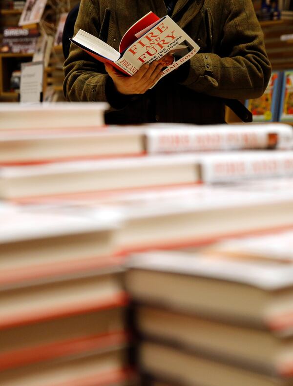 FILE - A customer looks at a copy of Michael Wolff's "Fire and Fury: Inside the Trump White House" as they go on sale at a bookshop, in London, Tuesday, Jan. 9, 2018. (AP Photo/Alastair Grant, File)