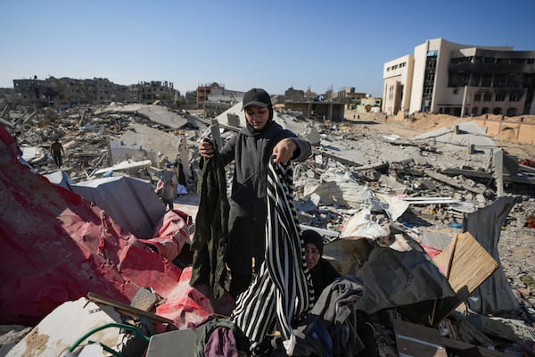 Nour Abu Al Zamar salvages items from under the rubble of her destroyed family home, in Rafah, southern Gaza Strip, Tuesday, Jan. 21, 2025, days after the ceasefire deal between Israel and Hamas came into effect. (AP Photo/Abdel Kareem Hana)