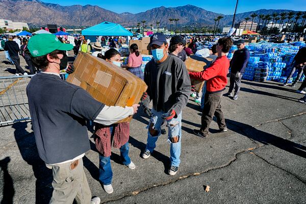 Volunteers unload a truck transporting donated items for residents effected by the Altadena Fire, at Santa Anita Park in Arcadia, Calif., Wednesday, Jan. 15, 2025. (AP Photo/Richard Vogel)