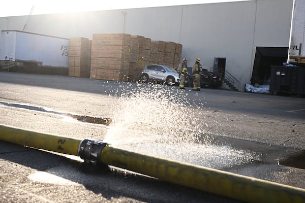 Firefighters stage outside a building where a plan crash occurred, Thursday, Jan. 2, 2025, in Fullerton, Calif. (AP Photo/Kyusung Gong)