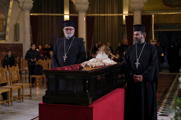 Greek Orthodox priests stand next to the casket of the late Archbishop Anastasios of Tirana, Durres and All Albania during a religious ceremony, a day before his funeral, inside the Cathedral of the Resurrection of Christ, in Tirana, Albania, Wednesday, Jan. 29, 2025. (AP Photo/Vlasov Sulaj)