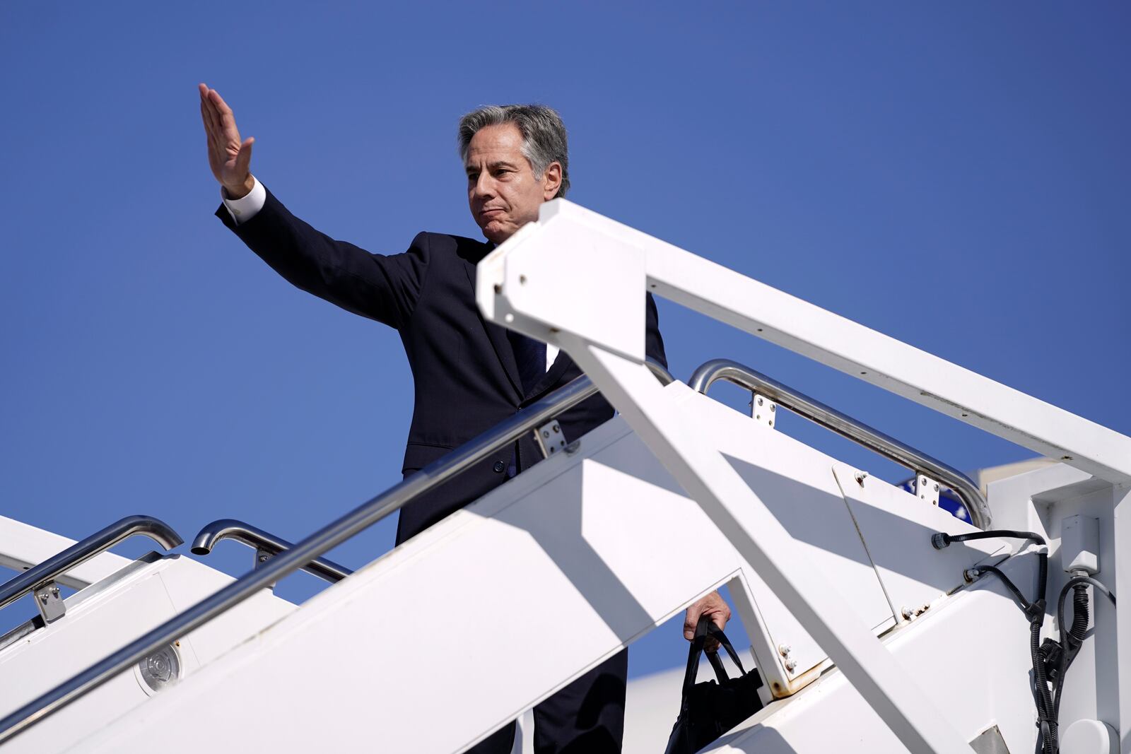 Secretary of State Antony Blinken waves as he boards a plane en route to the Middle East as he departs Joint Base Andrews, Md., Monday, Oct. 21, 2024. (Nathan Howard/Pool Photo via AP)