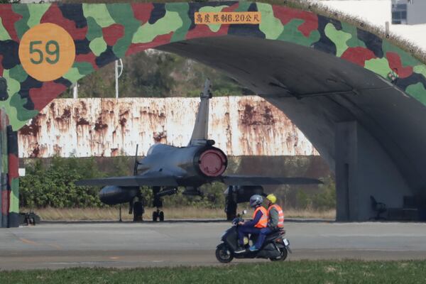 Taiwanese air ground force's members on a bike moves past airplane fort at an airbase in Hsinchu, northern Taiwan, Wednesday, Dec. 11, 2024, as Taiwan's Defense Ministry said Tuesday, it detected Chinese naval ships and military planes engaged in training. (AP Photo/Chiang Ying-ying)