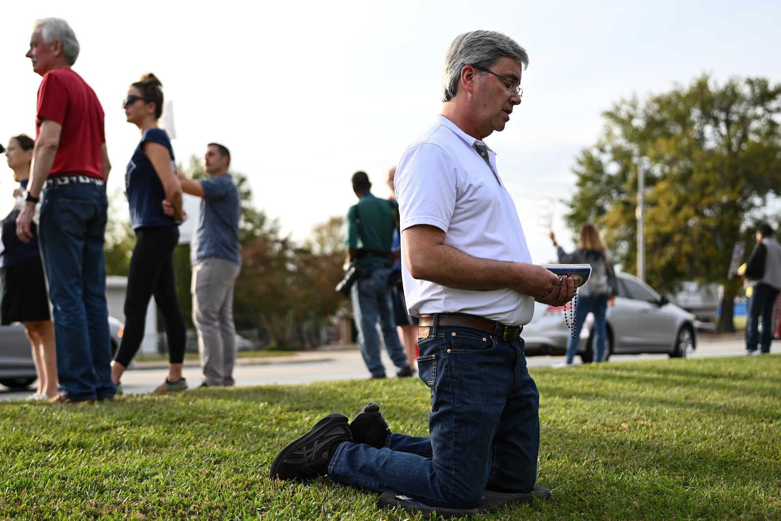 A protestor kneels to pray prior to the scheduled execution of Richard Moore, Friday, Nov. 1, 2024, outside of Broad River Correctional Institution in Columbia , S.C. (AP Photo/Matt Kelley)