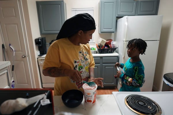 TiAnna Yeldell, left, helps her son Ivan, 8, right, in the kitchen last their home, Thursday, Nov. 14, 2024, in Missouri City, Texas. (AP Photo/Eric Gay)