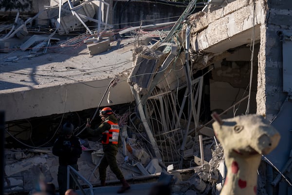 An officer from the home front command military unit examines the damage after a large piece of shrapnel from Houthi missile collapsed a school building in Ramat Gan, a suburb of Tel Aviv, Israel, Thursday, Dec. 19, 2024. (AP Photo/Ariel Schalit)