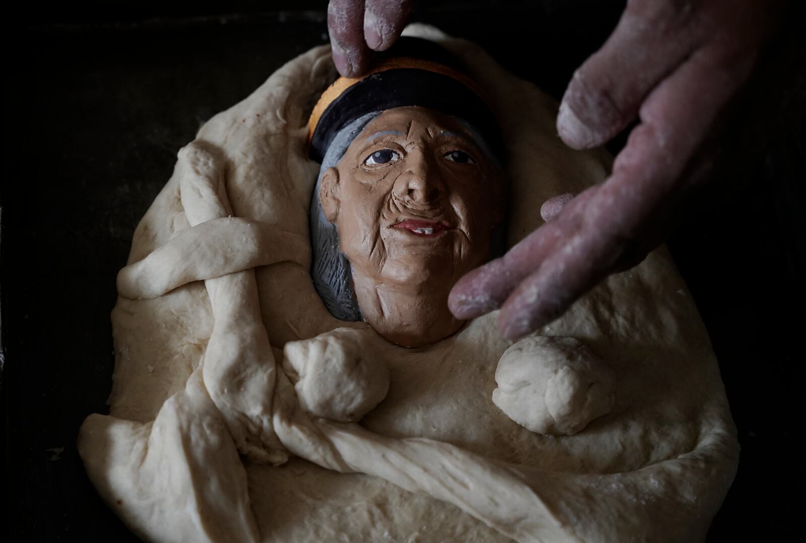 Artisan William Luna places a plaster mask of his grandmother on a piece of tantawawa bread during Day of the Dead celebrations in La Paz, Bolivia, Thursday, Oct. 31, 2024. (AP Photo/Freddy Barragan)