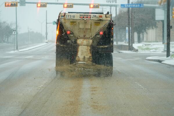 A truck treats a road for better driving conditions as snow falls Thursday, Jan. 9, 2025, in Dallas. (AP Photo/LM Otero)