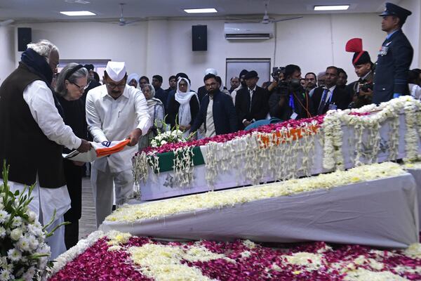 Congress party President Mallikarjun Kharge, left, and senior leader Sonia Gandhi are helped by an aide to place a flag on the casket of former Indian Prime Minister Manmohan Singh at their party headquarters in New Delhi, India, Saturday, Dec. 28, 2024. (AP Photo)