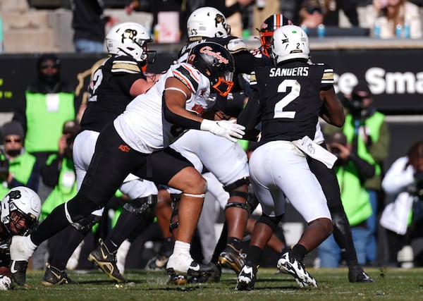 Oklahoma State defensive end DeSean Brown, front left, sacks Colorado quarterback Shedeur Sanders (2) in the second half of an NCAA college football game Friday, Nov. 29, 2024, in Boulder, Colo. (AP Photo/David Zalubowski)