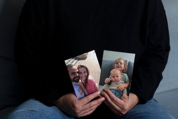 Yifat Zailer shows photos of her cousin, Shiri Bibas, center, her husband Yarden, left, and their sons Ariel, top right, and Kfir, who were taken hostage by Hamas militants, at her home in Herziliyya, Israel, Wednesday, Jan. 15, 2025. (AP Photo/Maya Alleruzzo)