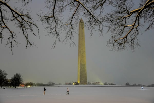 FILE - People walk near the Washington Monument during a winter snow storm in Washington, Jan. 6, 2025. (AP Photo/Matt Rourke, File)