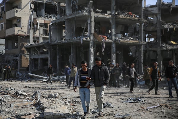 Palestinians walk amongst the destruction caused by the Israeli air and ground offensive, Sunday, Jan. 19, 2025, in Rafah, as a ceasefire deal between Israel and Hamas went into effect. (AP Photo/Mohammad Hajjar)