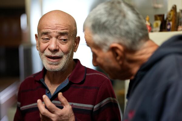 Suheil Hamwi, left, who spent 32 years in prison in Syria, reacts as a man shows him a picture of a missing Lebanese prisoner inside Syria, at Hamwi's home in Chekka, Lebanon, Tuesday, Dec. 10, 2024. (AP Photo/Hassan Ammar)