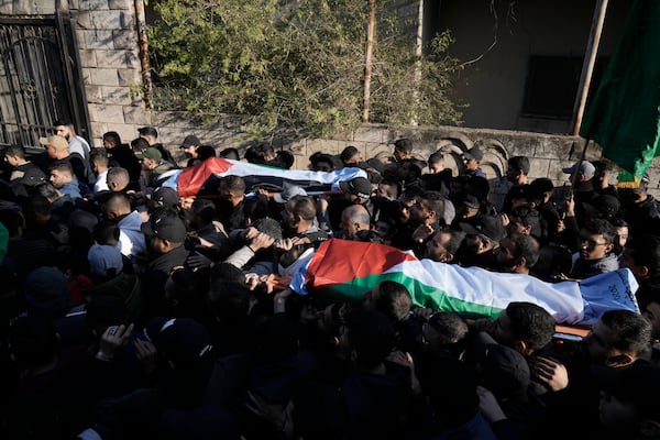 Mourners carry the bodies wrapped with the Palestinian flag, of Akram Abu Arrah and Mohammad Ghannam, both killed in an airstrike Israel said targeted a militant cell, during their funeral in the West Bank village of Al-Aqaba, Tuesday Dec. 3, 2024. (AP Photo/Majdi Muhammad)