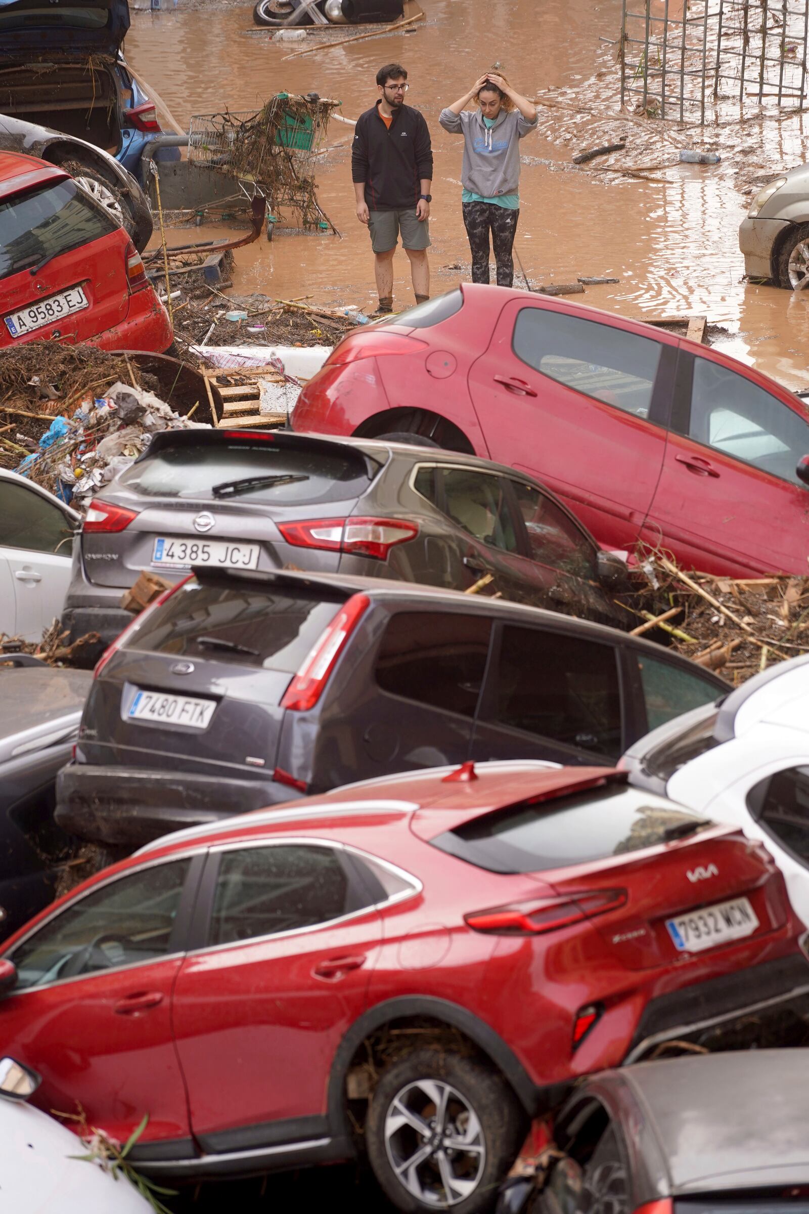 Residents look at cars piled up after being swept away by floods in Valencia, Spain, Wednesday, Oct. 30, 2024. (AP Photo/Alberto Saiz)