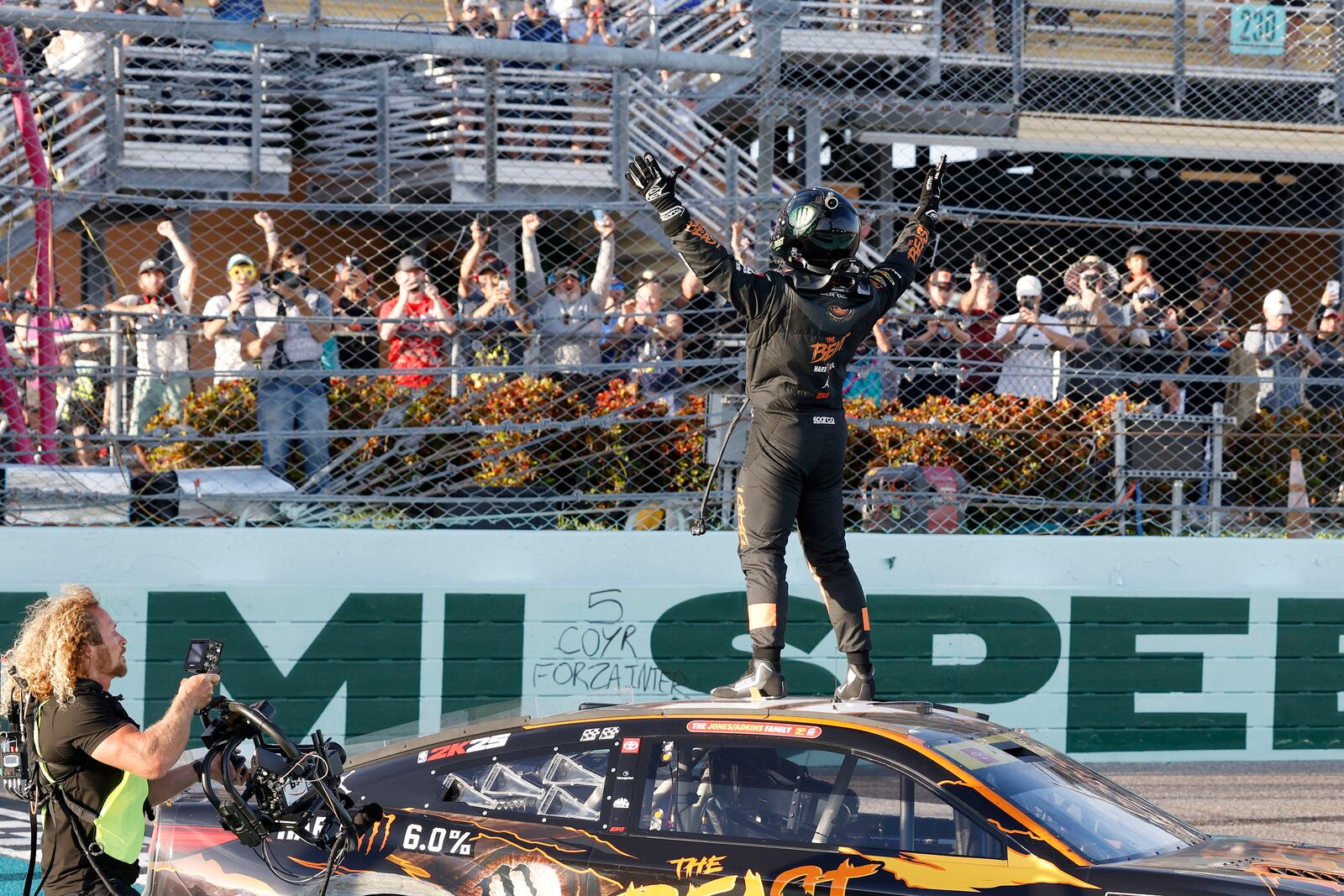 Tyler Reddick, front rifght, celebrates with fans at the finish line after winning a NASCAR Cup Series auto race at Homestead-Miami Speedway in Homestead, Fla., Sunday, Oct. 27, 2024. (AP Photo/Terry Renna)