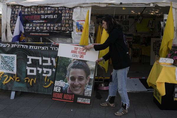 A man places a photo of Arbel Yehoud, next to a banner in Hebrew demanding the return of the hostages held by Hamas in Gaza Strip, at the entrance of a tent set up in Jerusalem, Monday, Jan. 27, 2025. (AP Photo/Mahmoud illean)