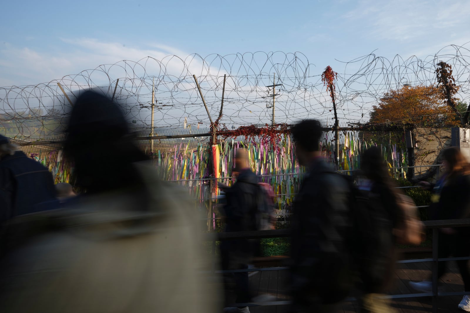 Visitors walk near a wire fence decorated with ribbons written with messages wishing for the reunification of the two Koreas at the Imjingak Pavilion in Paju, South Korea, Thursday, Oct. 31, 2024. (AP Photo/Lee Jin-man)