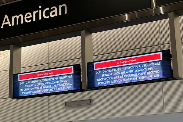 Signs display an "Emergency Alert" above an American Airlines counter in the terminal at Ronald Reagan Washington National Airport, Wednesday night, Jan. 29, 2025, in Arlington, Va. A jet with 60 passengers and four crew members aboard collided with an Army helicopter while landing at Ronald Reagan National Airport near Washington, prompting a large search-and-rescue operation in the nearby Potomac River. (AP Photo/Jeannie Ohm)