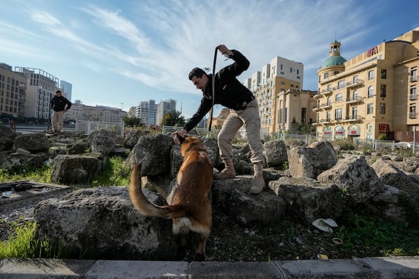 A Lebanese army soldier with a sniffer dog checks a road that leads to the parliament building while lawmakers gather to elect a president in Beirut, Lebanon, Thursday, Jan. 9, 2025. (AP Photo/Bilal Hussein)