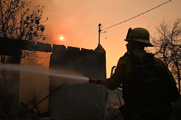 A firefighters waters down a home after the Eaton Fire burns in Altadena, Calif., Thursday, Jan. 9, 2025. (AP Photo/Nic Coury)