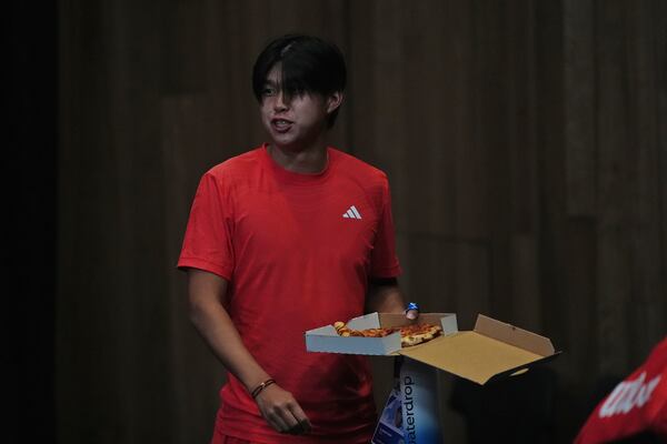 Learner Tien of the U.S. eats pizza as he leaves from a press conference for his second round match against Daniil Medvedev of Russia at the Australian Open tennis championship in Melbourne, Australia, in the early hours of Friday, Jan. 17, 2025. (AP Photo/Ng Han Guan)