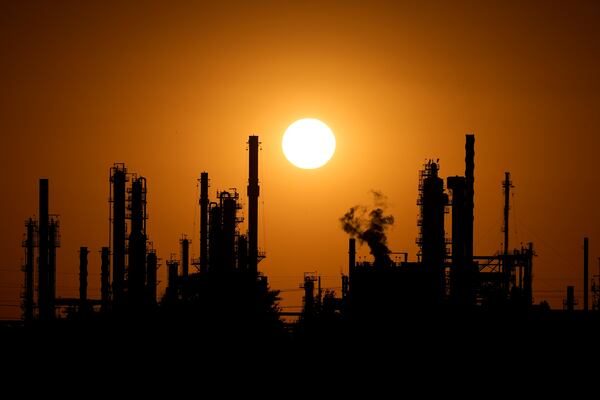 The CHS oil refinery is silhouetted against the setting sun Saturday, Sept. 28, 2024, in McPherson, Kan. (AP Photo/Charlie Riedel)