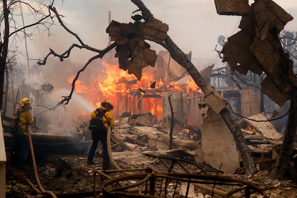 Firefighters battle the Palisades Fire as it burns a structure in the Pacific Palisades neighborhood of Los Angeles, Wednesday, Jan. 8, 2025. (AP Photo/Etienne Laurent)