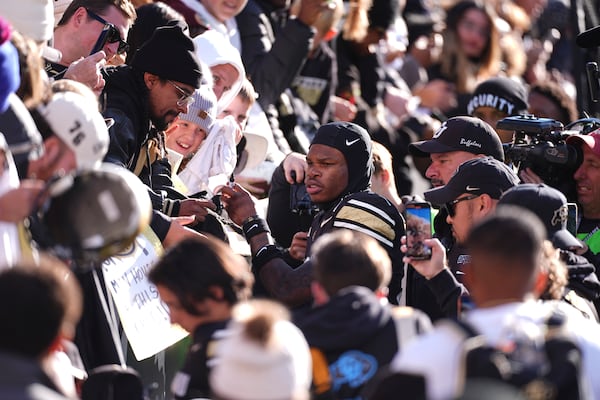 Colorado wide receiver Travis Hunter, center, is surrounded by fans as he heads to the locker room after an NCAA college football game against Oklahoma State, Friday, Nov. 29, 2024, in Boulder, Colo. (AP Photo/David Zalubowski)