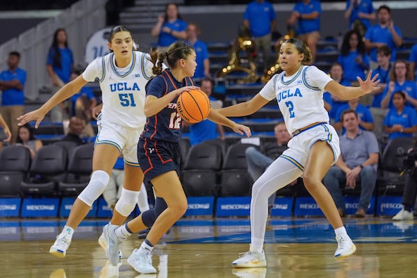 Pepperdine guard Makena Mastora (12) center, attacks against UCLA center Lauren Betts (51) and UCLA guard Avary Cain (2) during a women's NCAA college basketball game, Tuesday, Nov. 12, 2024, in Los Angeles. (AP Photo/Damian Dovarganes)