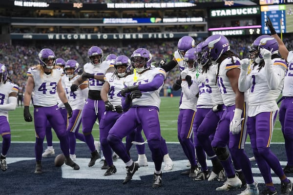 Minnesota Vikings linebacker Dallas Turner (15), center, celebrates with teammates after intercepting a pass during the first half of an NFL football game against the Seattle Seahawks, Sunday, Dec. 22, 2024, in Seattle. (AP Photo/Lindsey Wasson)