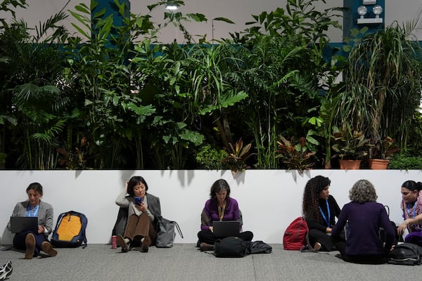 Attendees sit during a break while at the COP29 U.N. Climate Summit, Monday, Nov. 18, 2024, in Baku, Azerbaijan. (AP Photo/Joshua A. Bickel)