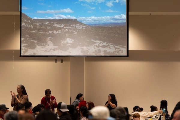 People clap as an image of land recently purchased by the Confederated Tribes of Siletz Indians is displayed on a screen during a lunch for tribal members and guests before a powwow at Chinook Winds Casino Resort, Saturday, Nov. 16, 2024, in Lincoln City, Ore. (AP Photo/Jenny Kane)