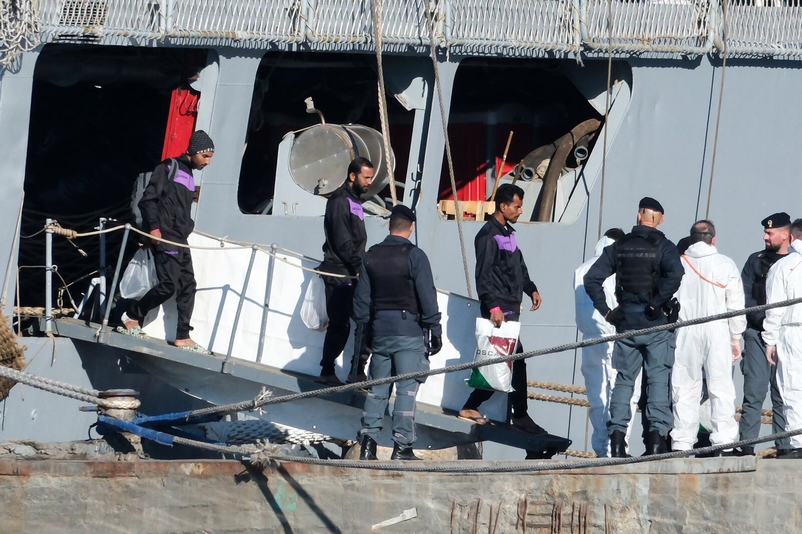 Migrants disembark from the Italian navy ship Libra at the port of Shengjin, northwestern Albania, Friday, Nov. 8, 2024, as a second group of eight migrants were intercepted in international waters is processed in a reception facility despite the failure with the first group in October. (AP Photo/Vlasov Sulaj)